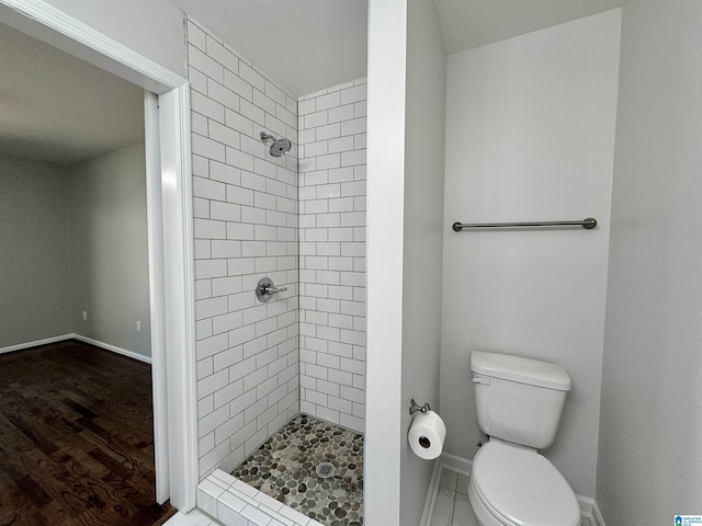 bathroom with toilet, a stall shower, baseboards, and wood finished floors