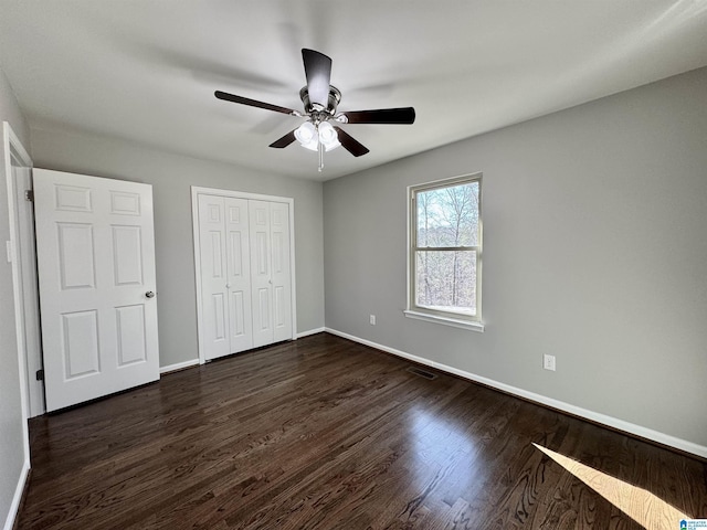 unfurnished bedroom with dark wood-type flooring, a closet, visible vents, and baseboards