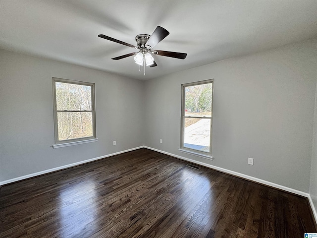 unfurnished room with a ceiling fan, baseboards, visible vents, and dark wood-style flooring