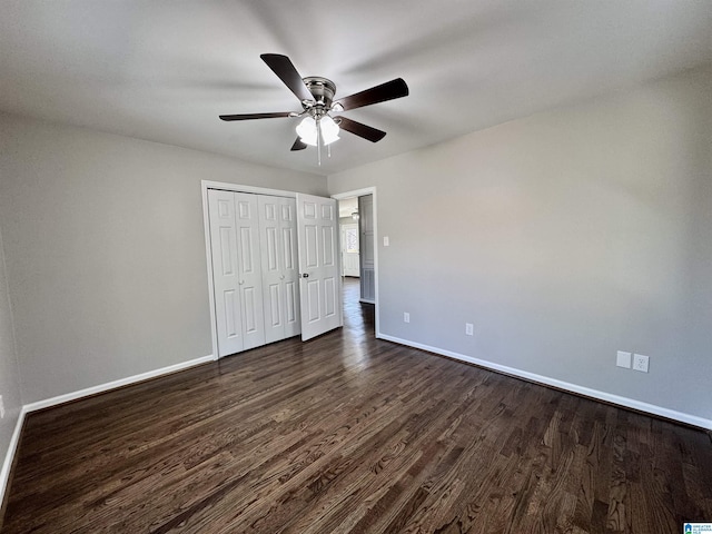 unfurnished bedroom featuring a closet, dark wood finished floors, and baseboards