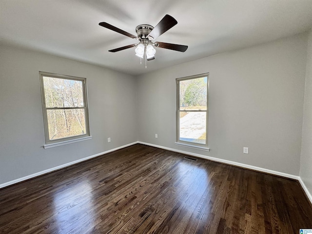 unfurnished room with visible vents, dark wood finished floors, baseboards, and ceiling fan