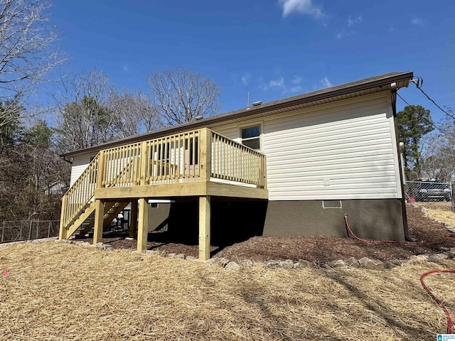 back of house featuring stairs, a wooden deck, and fence