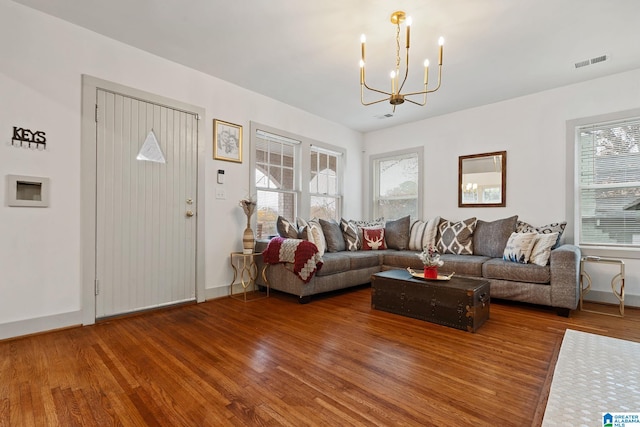 living area with a chandelier, visible vents, baseboards, and wood finished floors