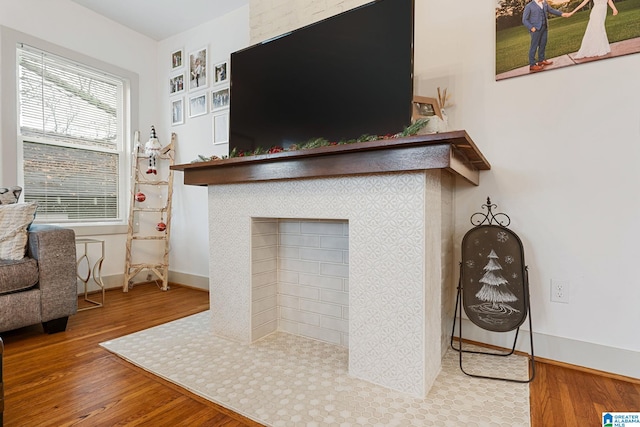 living area featuring a fireplace, wood finished floors, and baseboards