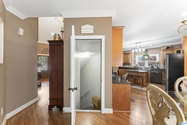 kitchen featuring brown cabinetry, dark countertops, ornamental molding, decorative light fixtures, and stainless steel appliances