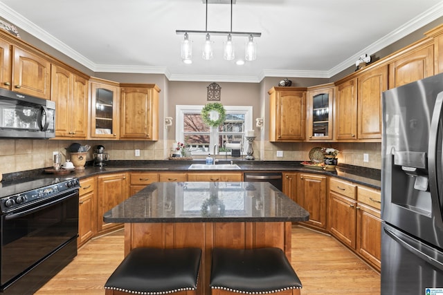 kitchen featuring a kitchen breakfast bar, black appliances, glass insert cabinets, and a center island