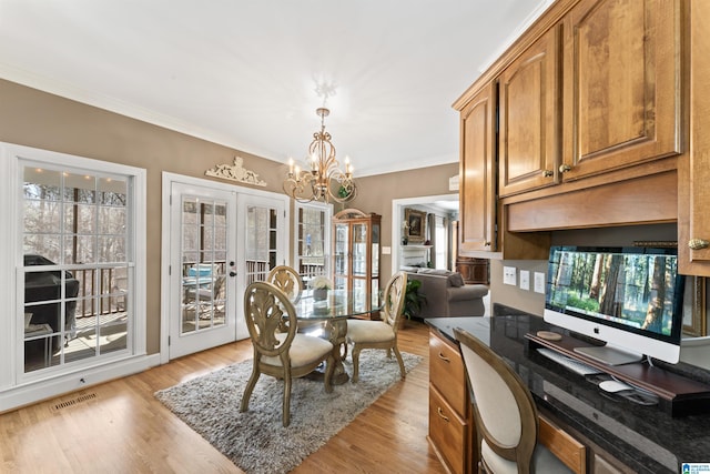 dining area featuring a chandelier, light wood-style flooring, visible vents, ornamental molding, and french doors