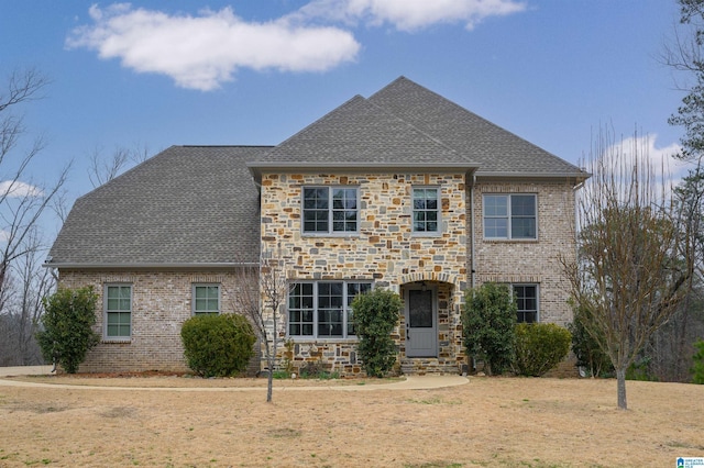 view of front of house with entry steps, stone siding, brick siding, and roof with shingles