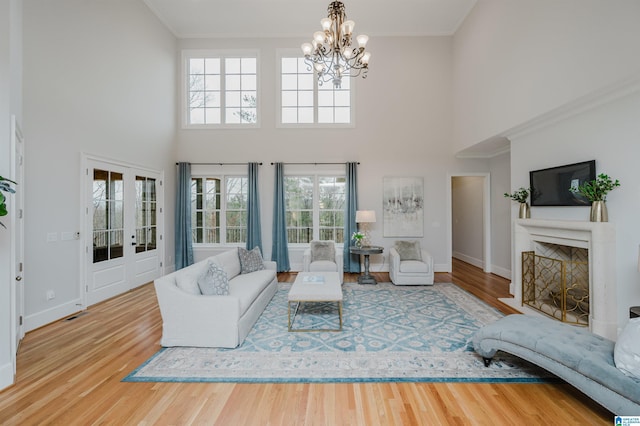 living area featuring a fireplace with flush hearth, crown molding, baseboards, and wood finished floors