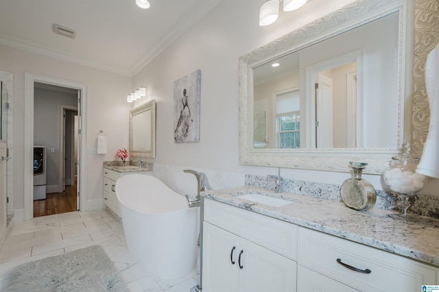 bathroom with ornamental molding, washer / clothes dryer, a freestanding bath, and vanity