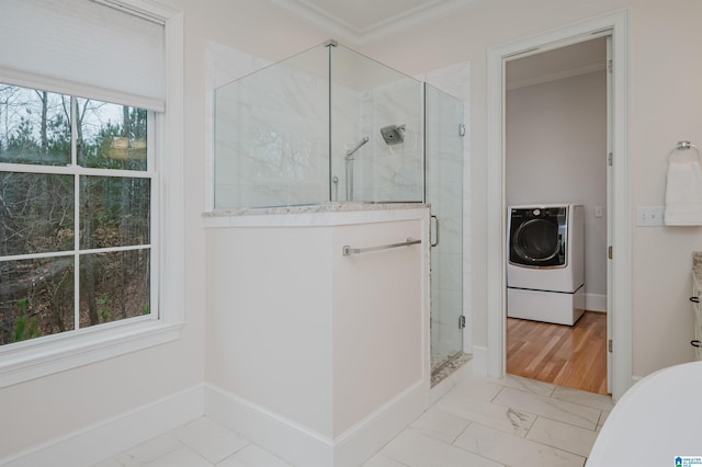 bathroom featuring marble finish floor, washer / clothes dryer, a shower stall, and crown molding