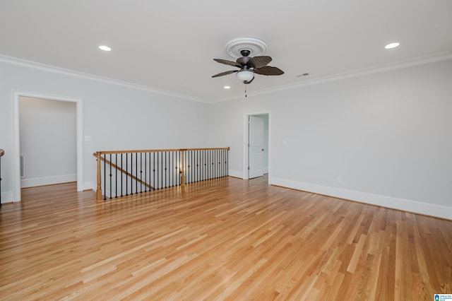 empty room featuring baseboards, light wood-type flooring, visible vents, and crown molding