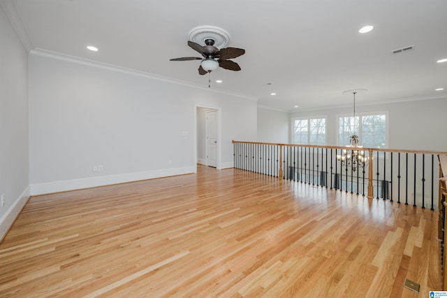 unfurnished room featuring ornamental molding, light wood-type flooring, visible vents, and baseboards