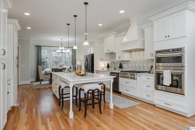 kitchen with appliances with stainless steel finishes, a breakfast bar, decorative light fixtures, a center island, and light countertops