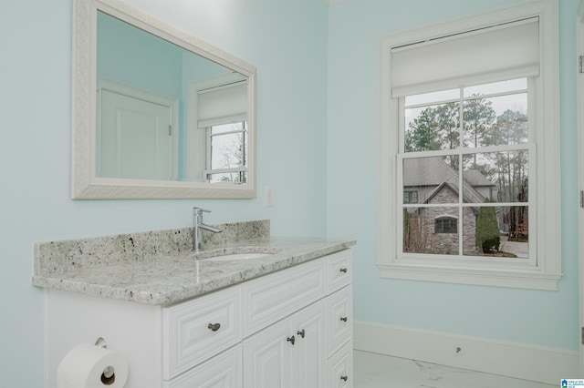 half bath featuring marble finish floor, vanity, and baseboards