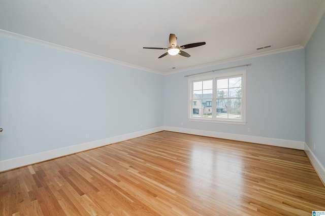 empty room featuring light wood-style floors, visible vents, crown molding, and baseboards