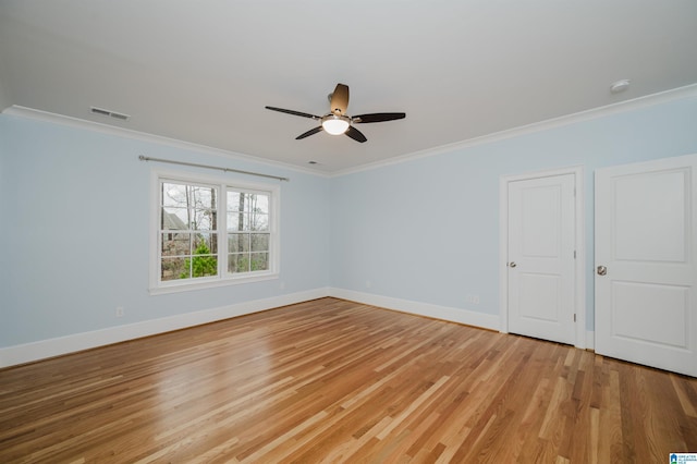 empty room with baseboards, light wood-type flooring, and crown molding