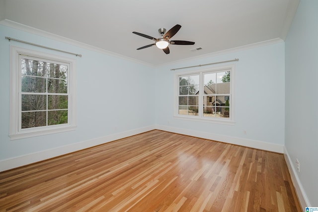 empty room featuring light wood-style floors, visible vents, ornamental molding, and baseboards