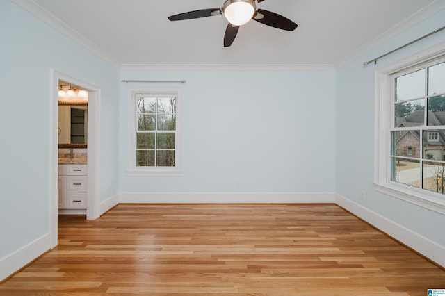 unfurnished room featuring baseboards, ceiling fan, light wood-type flooring, and crown molding