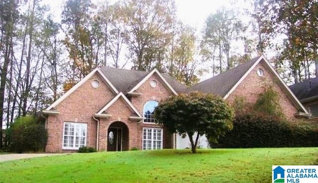 traditional-style house featuring a front yard and brick siding