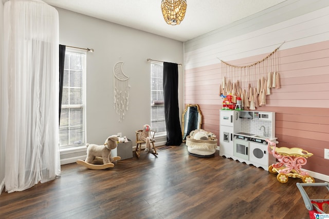 playroom featuring dark wood-style flooring and wooden walls