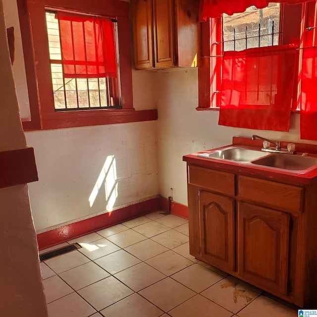 kitchen with light tile patterned flooring, a sink, visible vents, baseboards, and light countertops