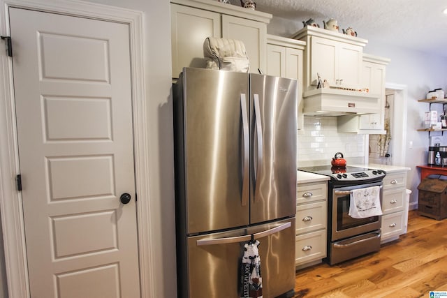 kitchen featuring light countertops, appliances with stainless steel finishes, backsplash, light wood finished floors, and custom range hood