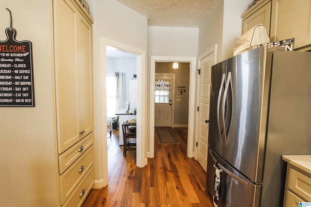 kitchen featuring dark wood-style flooring, freestanding refrigerator, cream cabinets, light countertops, and a textured ceiling