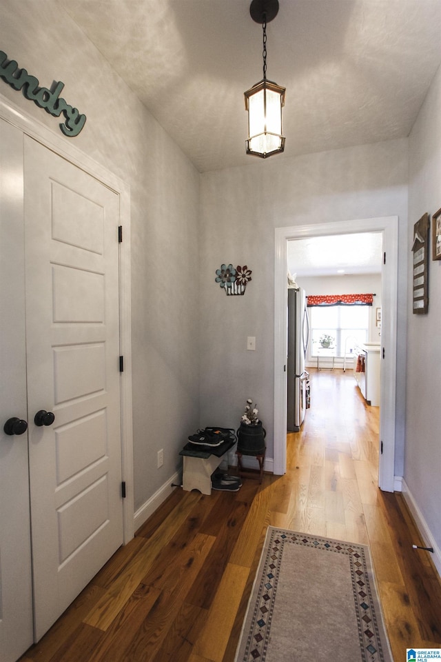 hall with baseboards and wood finished floors