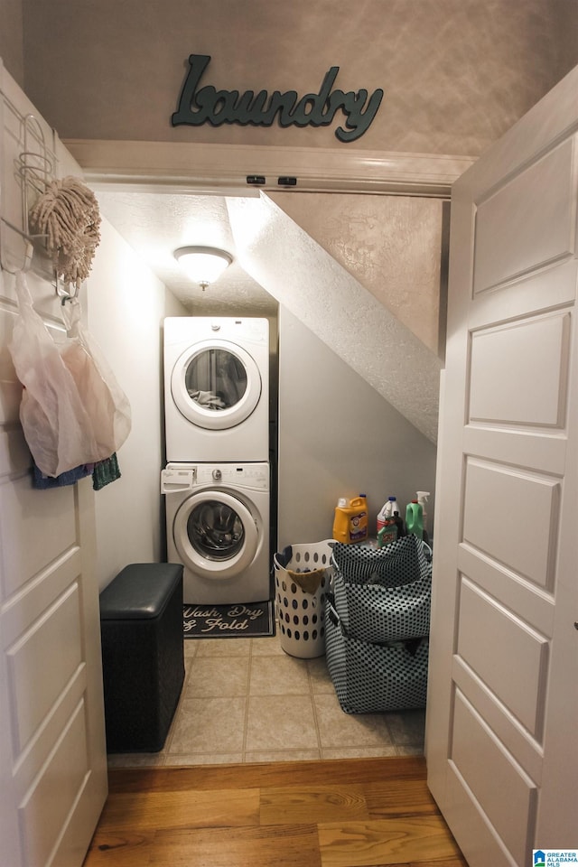 clothes washing area with laundry area, wood finished floors, and stacked washer / drying machine