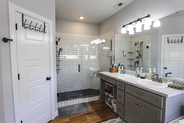 bathroom with a stall shower, visible vents, vanity, and wood finished floors