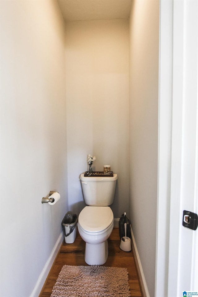 bathroom with toilet, baseboards, and wood finished floors