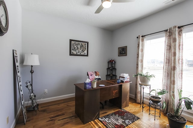 office space featuring dark wood-style floors, visible vents, a ceiling fan, and baseboards