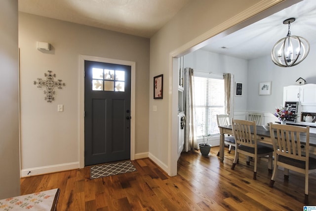 entryway featuring dark wood finished floors, baseboards, and an inviting chandelier