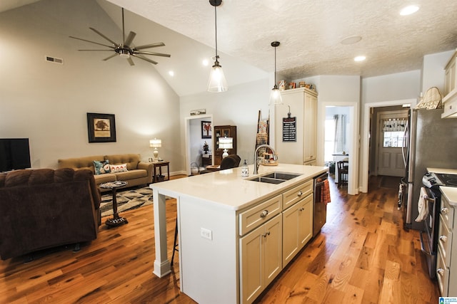 kitchen featuring open floor plan, a kitchen island with sink, stainless steel appliances, light countertops, and a sink