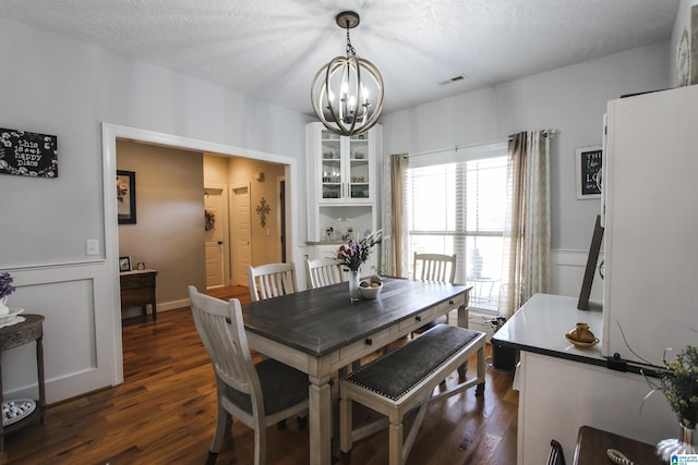 dining area featuring visible vents, wainscoting, dark wood-style floors, a textured ceiling, and a chandelier