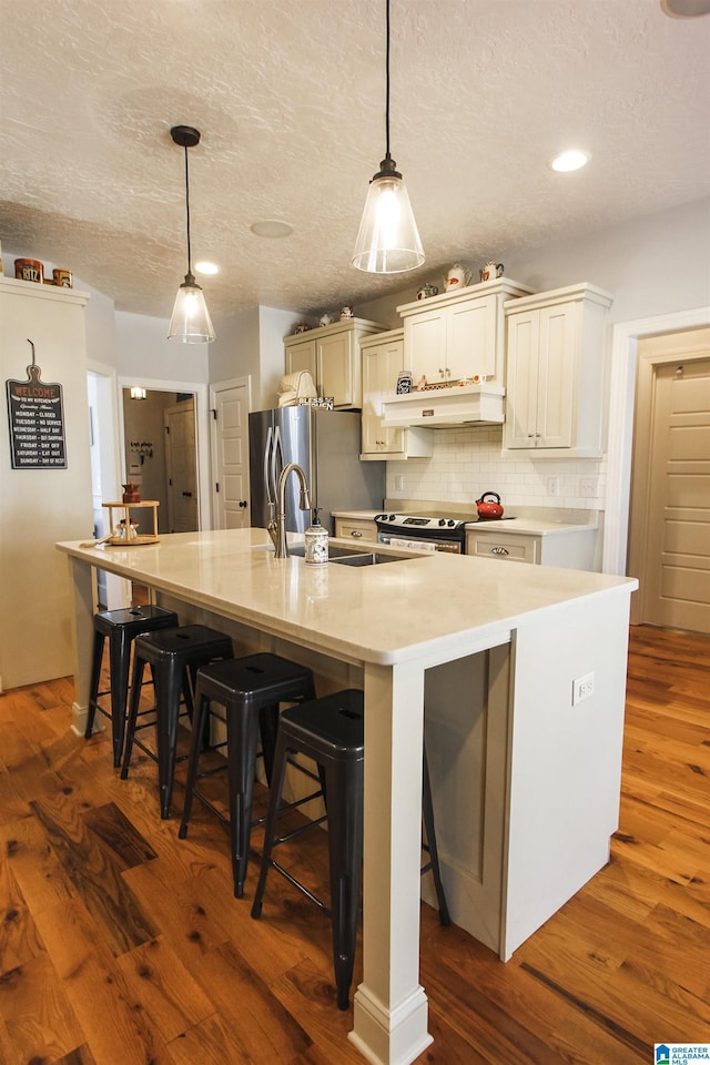 kitchen with a breakfast bar, light countertops, and a large island with sink