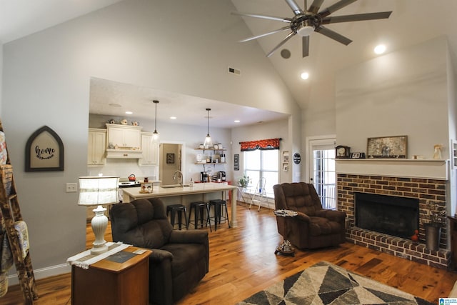 living room featuring a fireplace, visible vents, ceiling fan, wood finished floors, and baseboards