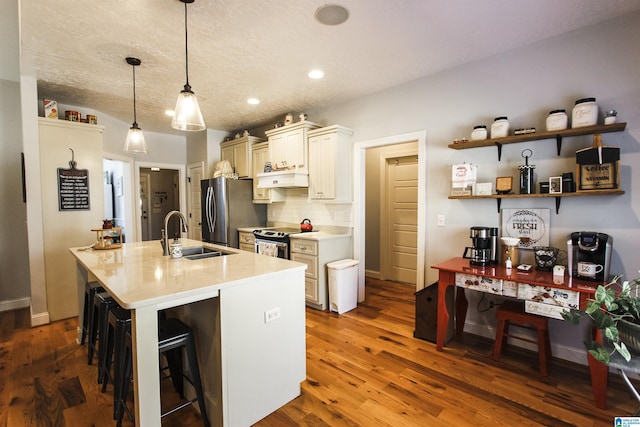 kitchen with a breakfast bar, pendant lighting, stainless steel appliances, light countertops, and a sink