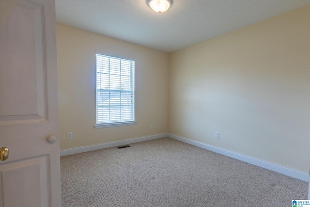 spare room with light carpet, baseboards, and visible vents