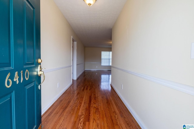 corridor with baseboards and wood finished floors