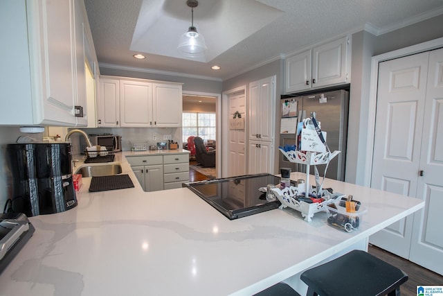 kitchen featuring light countertops, freestanding refrigerator, decorative light fixtures, and white cabinets