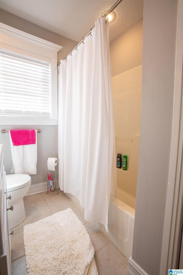 bathroom featuring baseboards, toilet, tile patterned flooring, shower / bath combination with curtain, and a textured ceiling