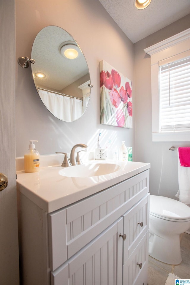 full bath with a textured ceiling, toilet, and vanity