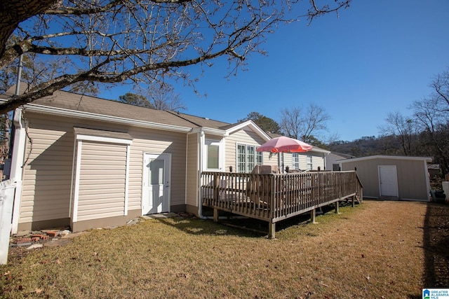 rear view of property featuring a deck, a yard, a shed, and an outbuilding