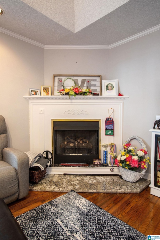 interior space featuring a fireplace with raised hearth, crown molding, a textured ceiling, and wood finished floors