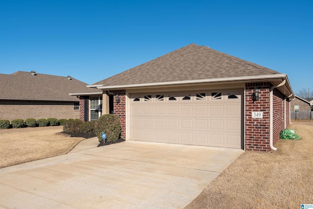 ranch-style home with a shingled roof, concrete driveway, brick siding, and an attached garage