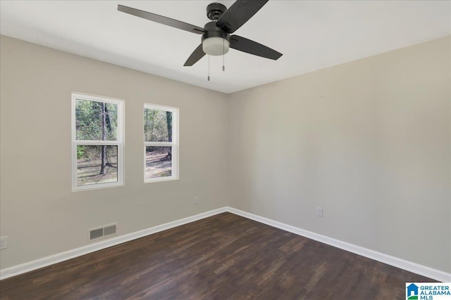 spare room featuring dark wood-style flooring, visible vents, ceiling fan, and baseboards