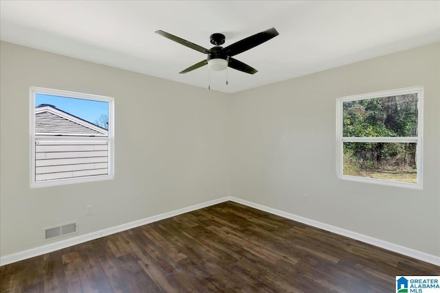 unfurnished room with a ceiling fan, baseboards, visible vents, and dark wood-style flooring