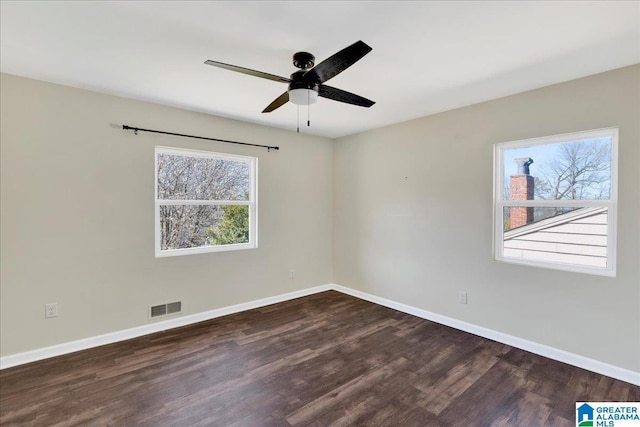 empty room featuring dark wood finished floors, visible vents, and baseboards